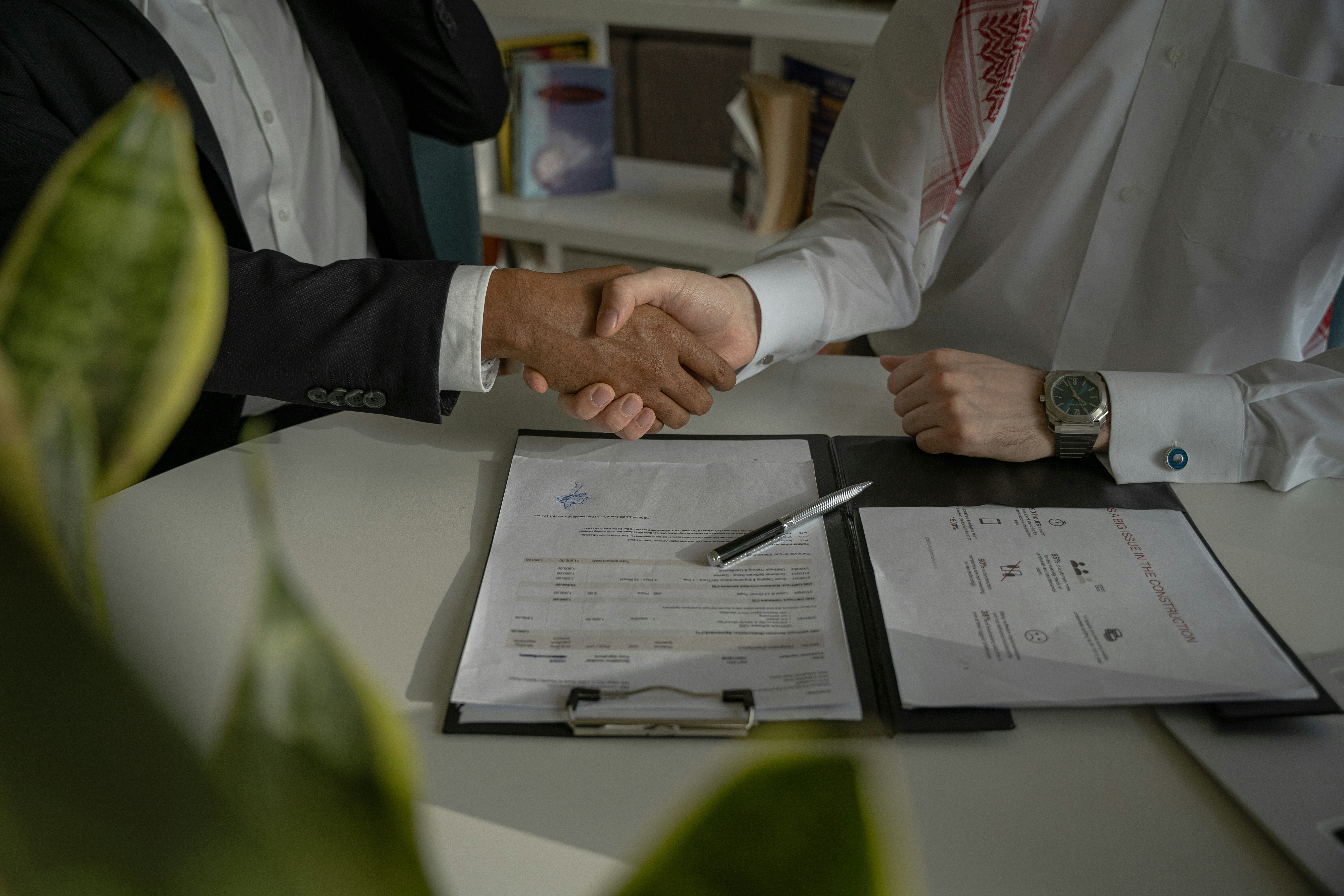 two people shaking hands over a singed contract