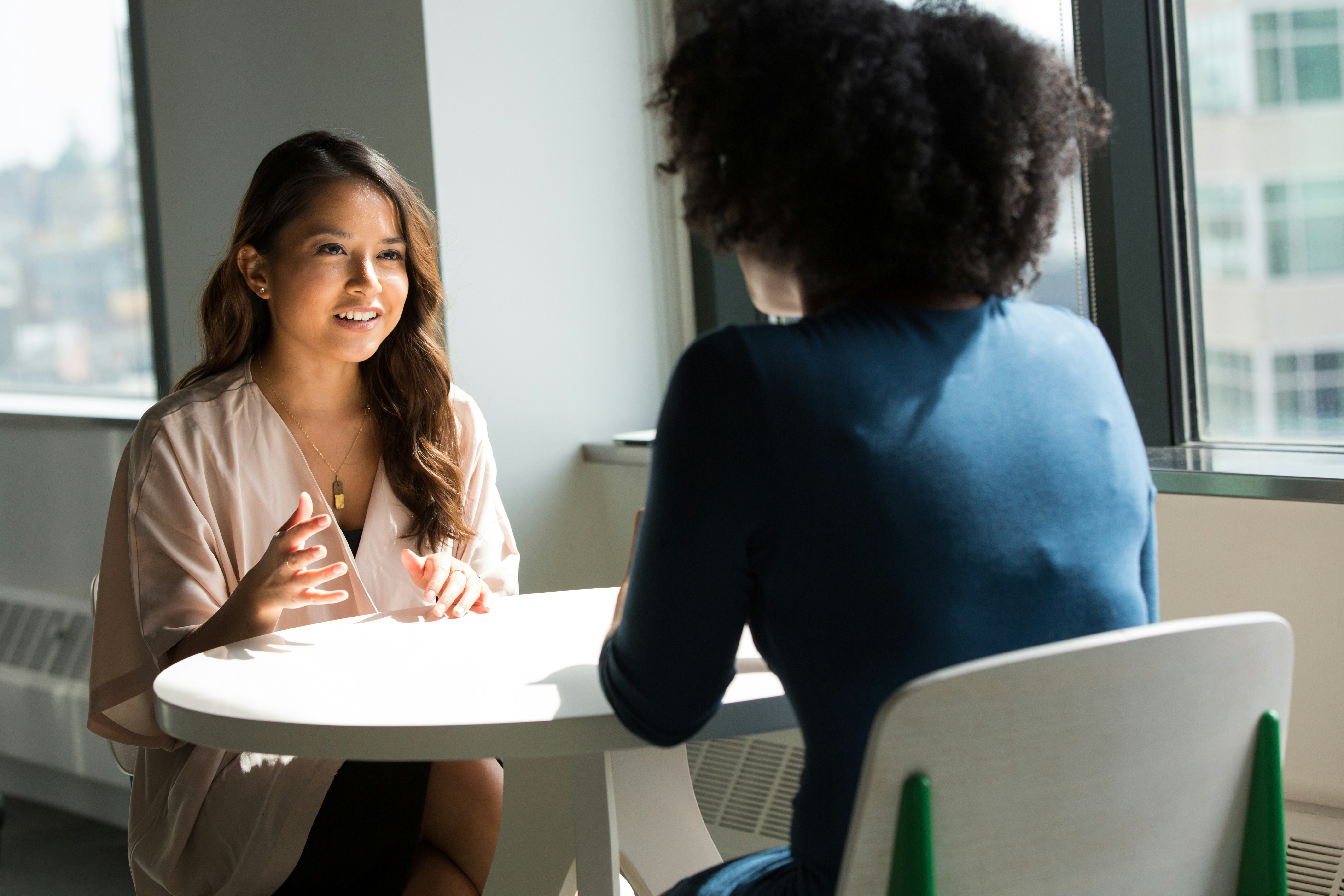 Two women at a sunlit white table having a meeting