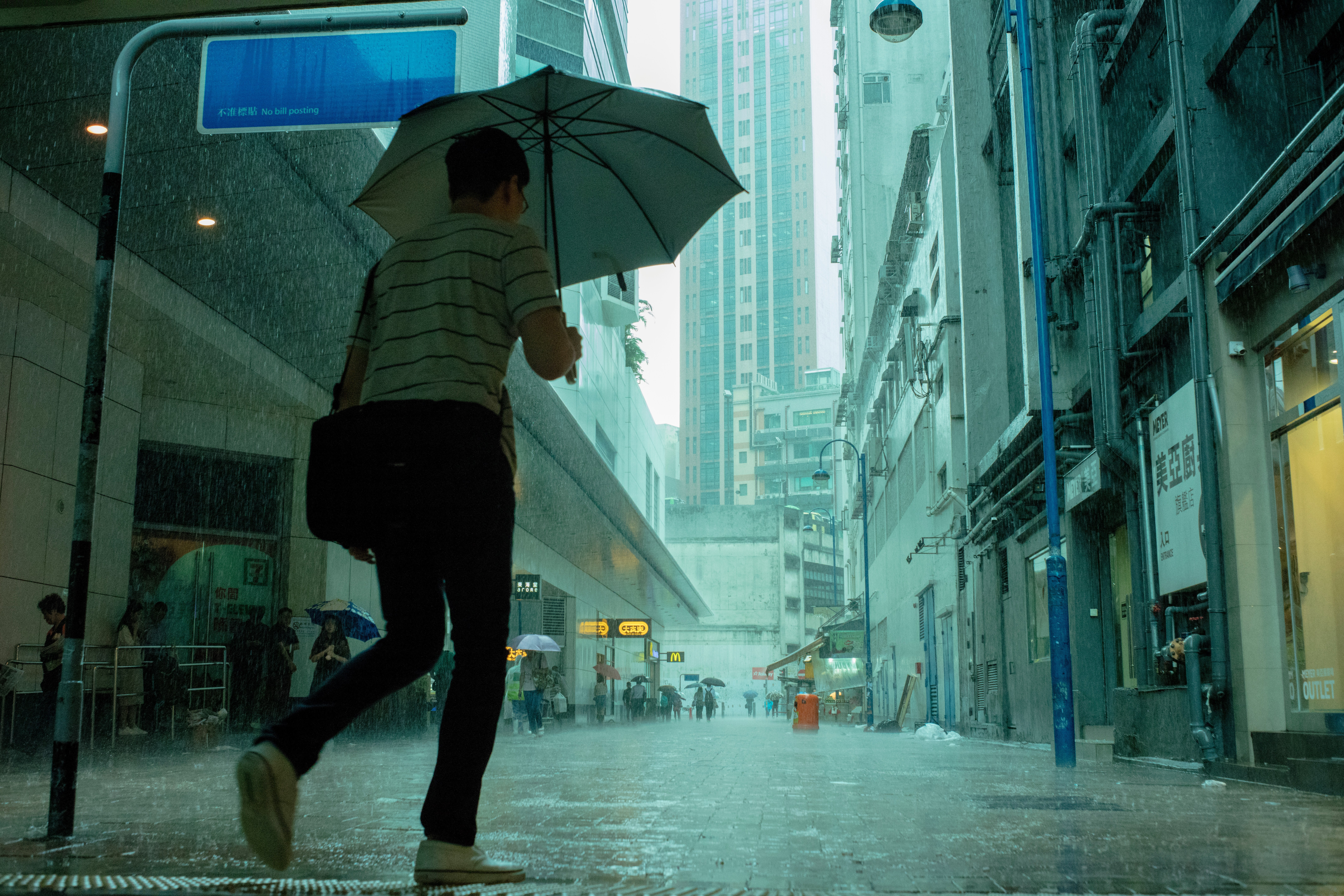 A woman walking down a Hong Kong street in the rain with an umbrella