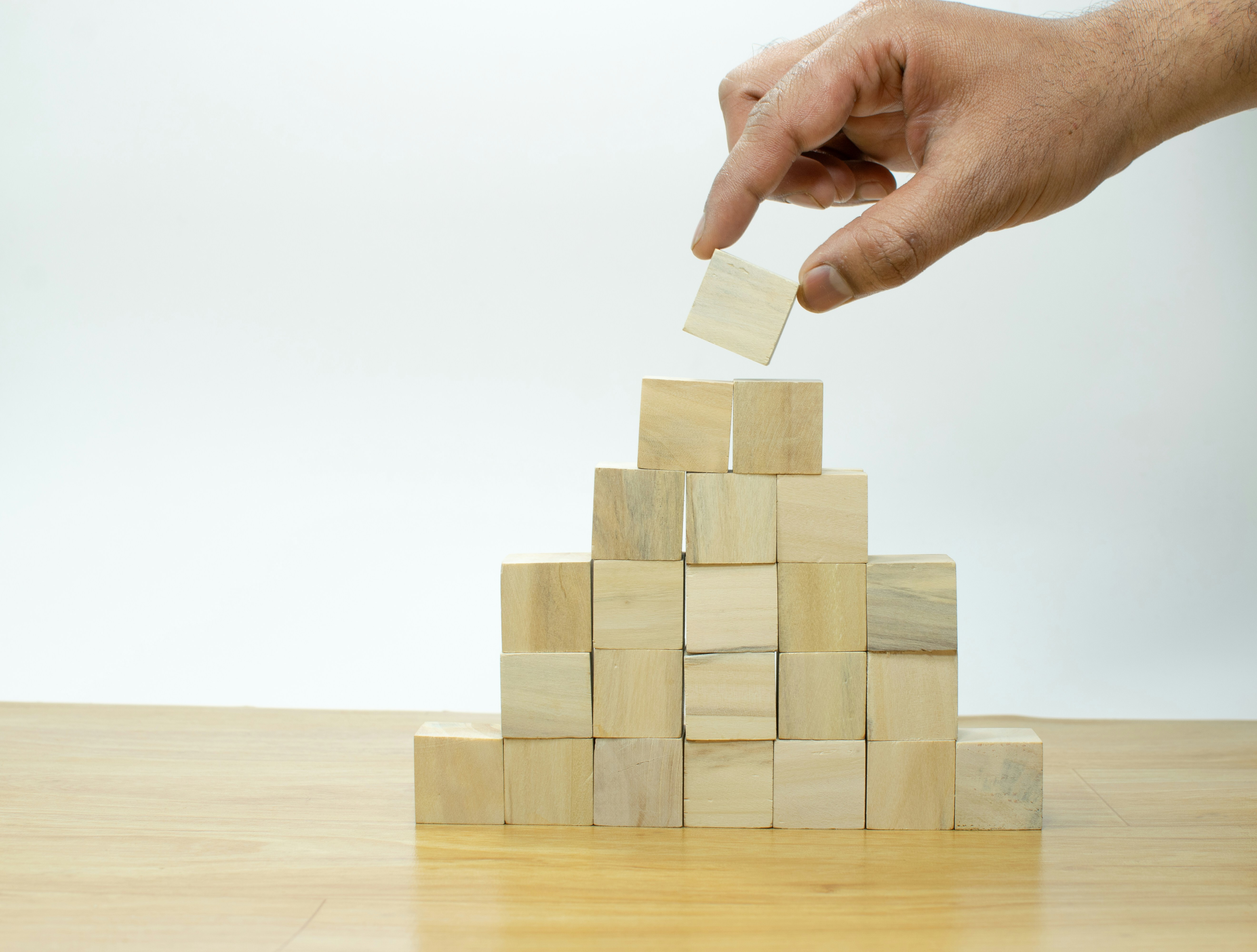 A hand stacking blocks into a pyramid