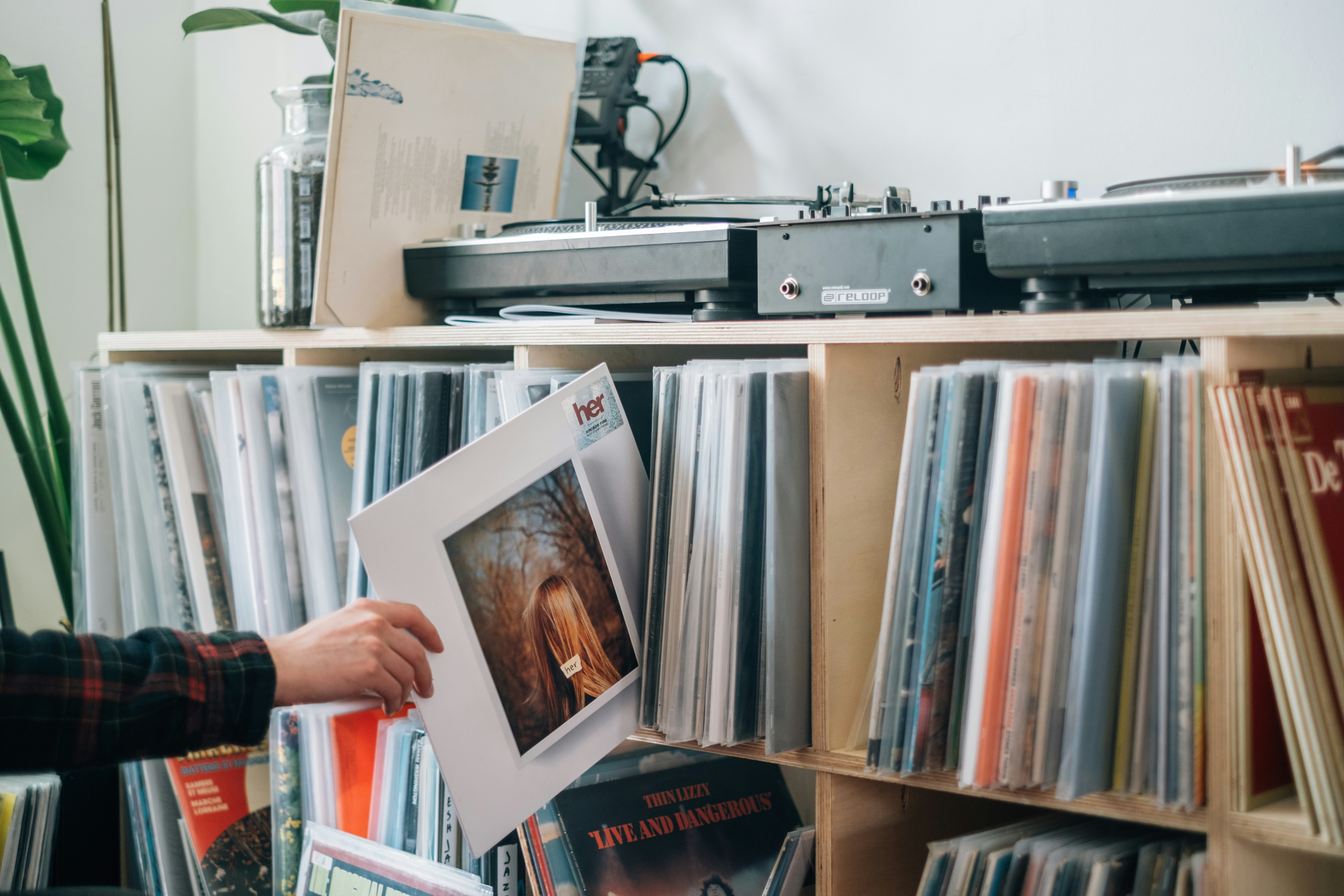 A collection of vinyl records, with a record being selected for play