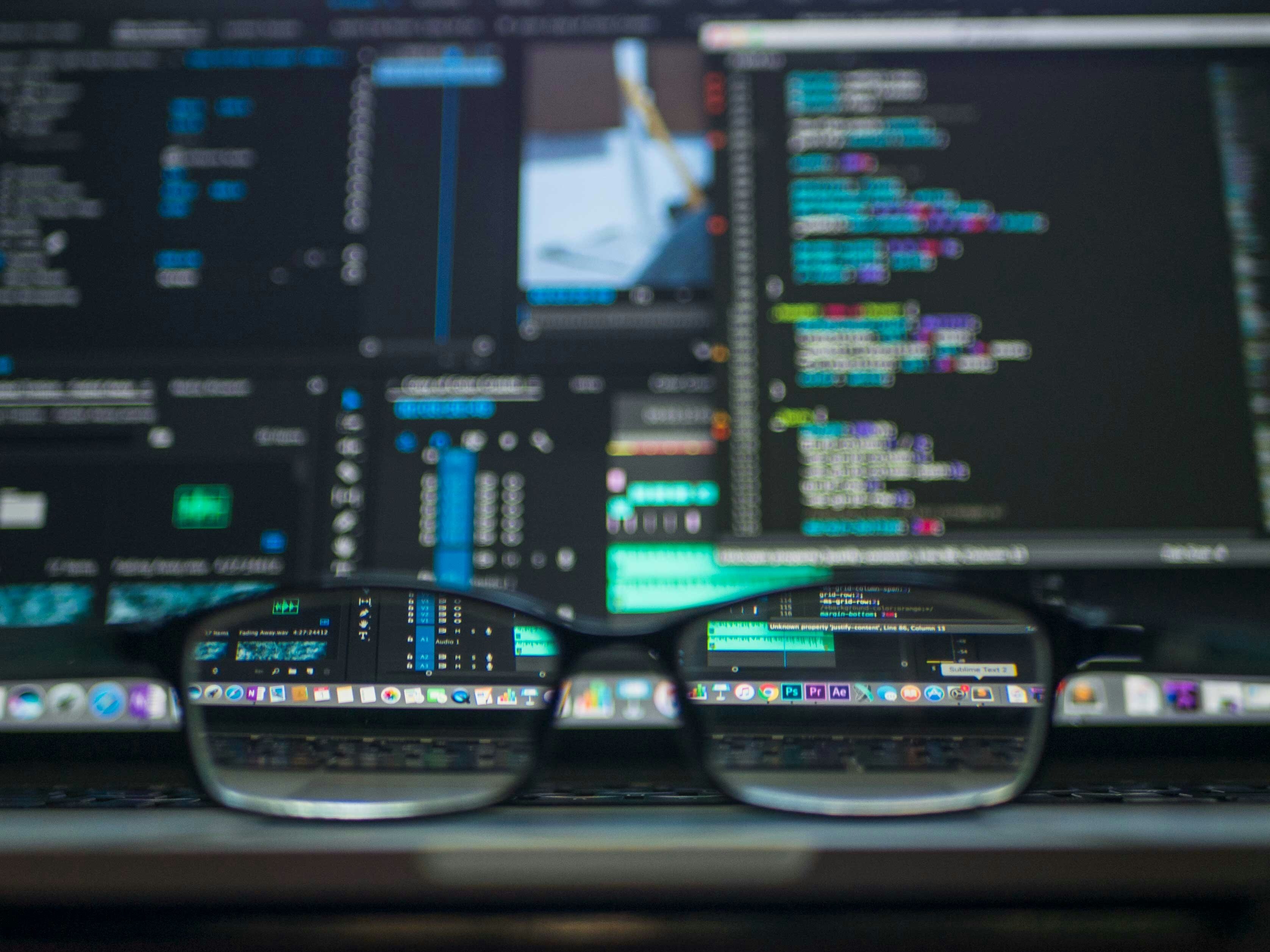 a pair of glasses in front of a computer screen displaying code in windows