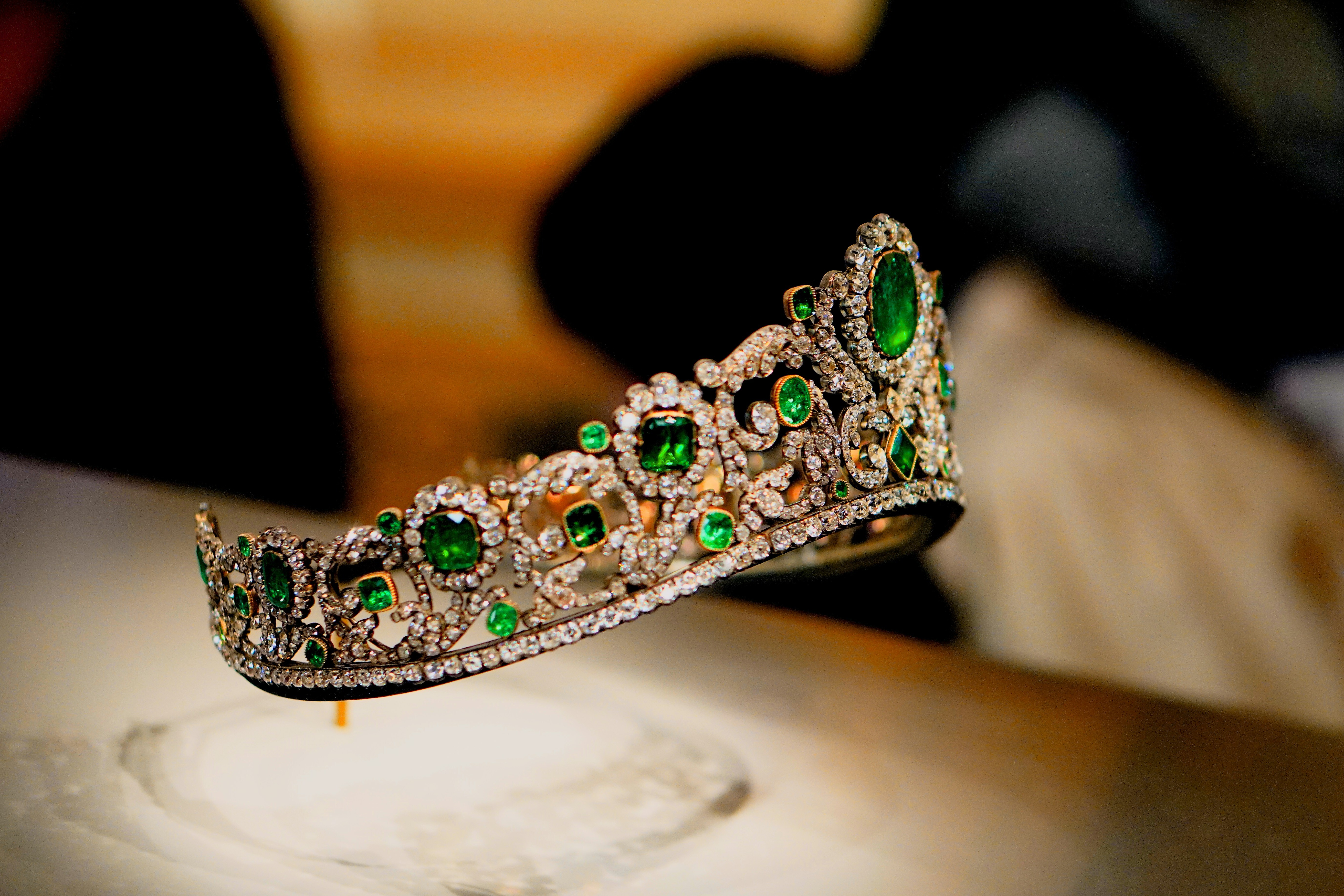 A gold and emerald tiara sitting in a display case