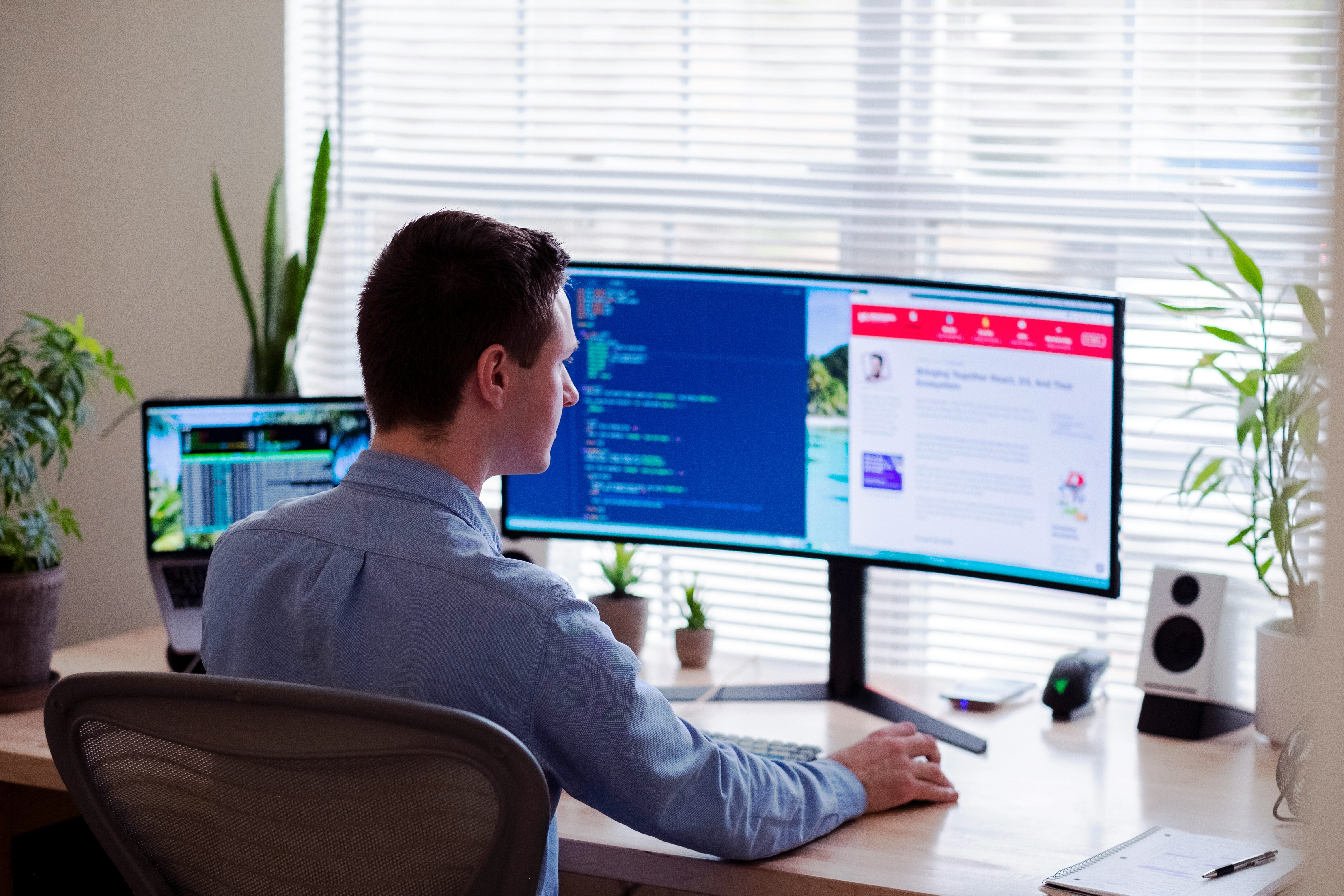 A man sitting in front of a computer with multiple windows open on screen, working.